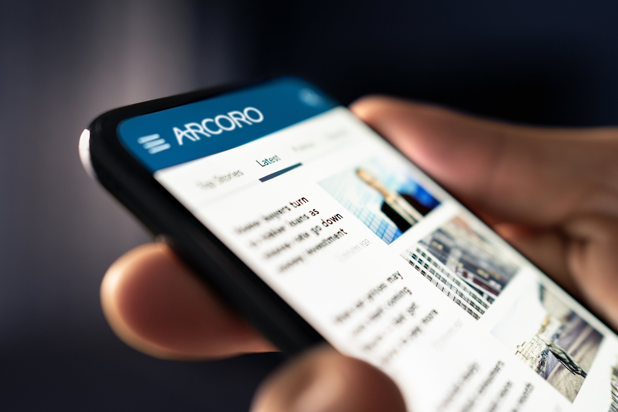 Mobile phone with Arcoro banner and news articles